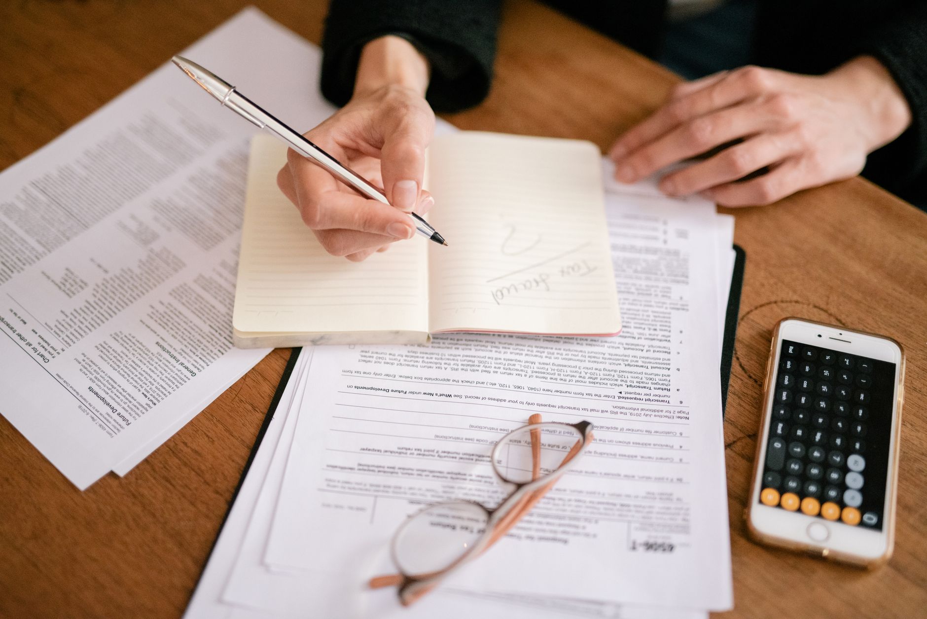 Documents, a calculator and a notebook on a desk.