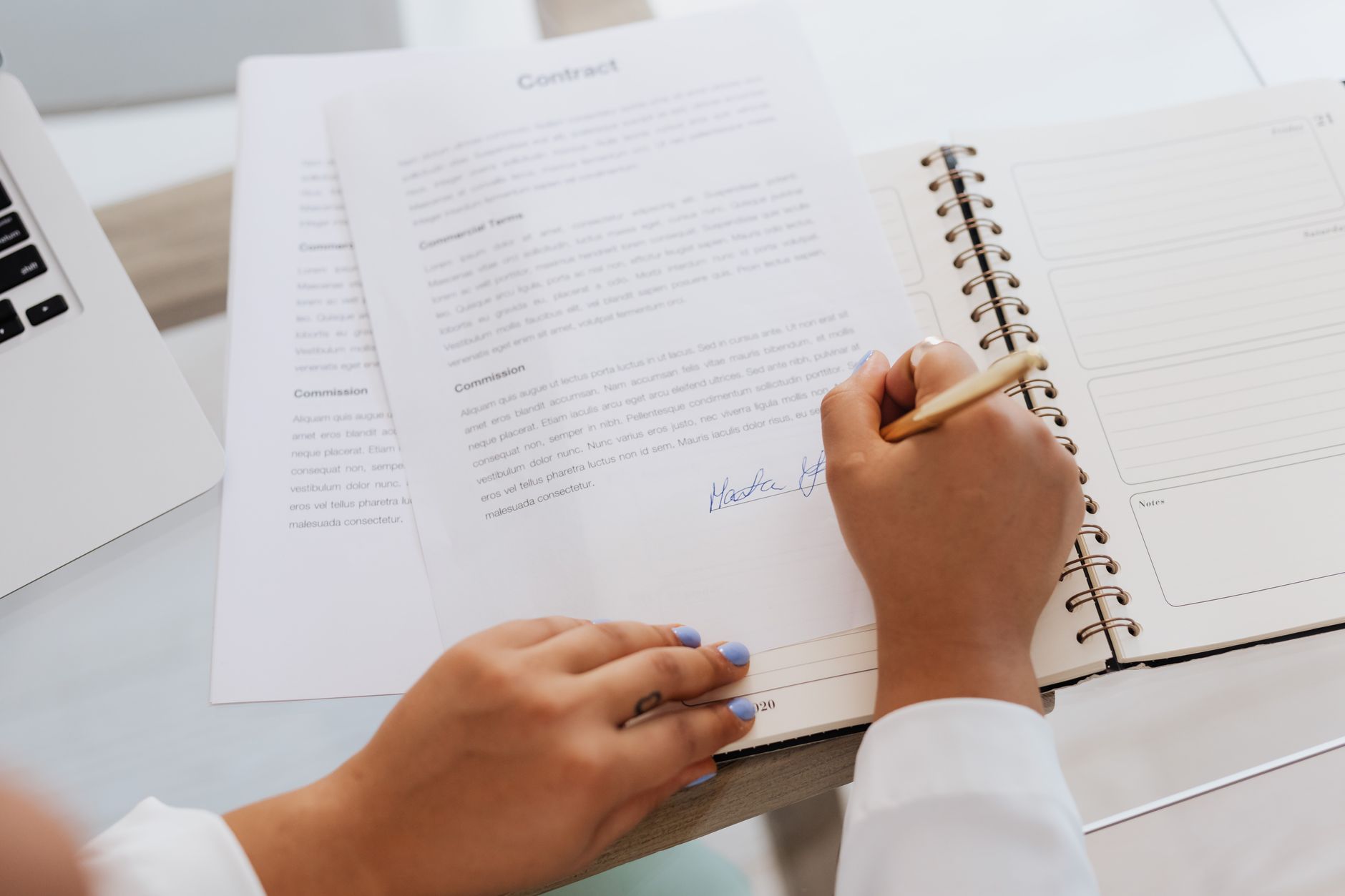 Company documents and a laptop on an office desk, prepared for a bank.