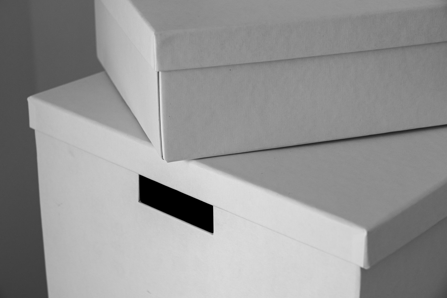 Two white cardboard archive boxes stacked, one with a blank label slot.