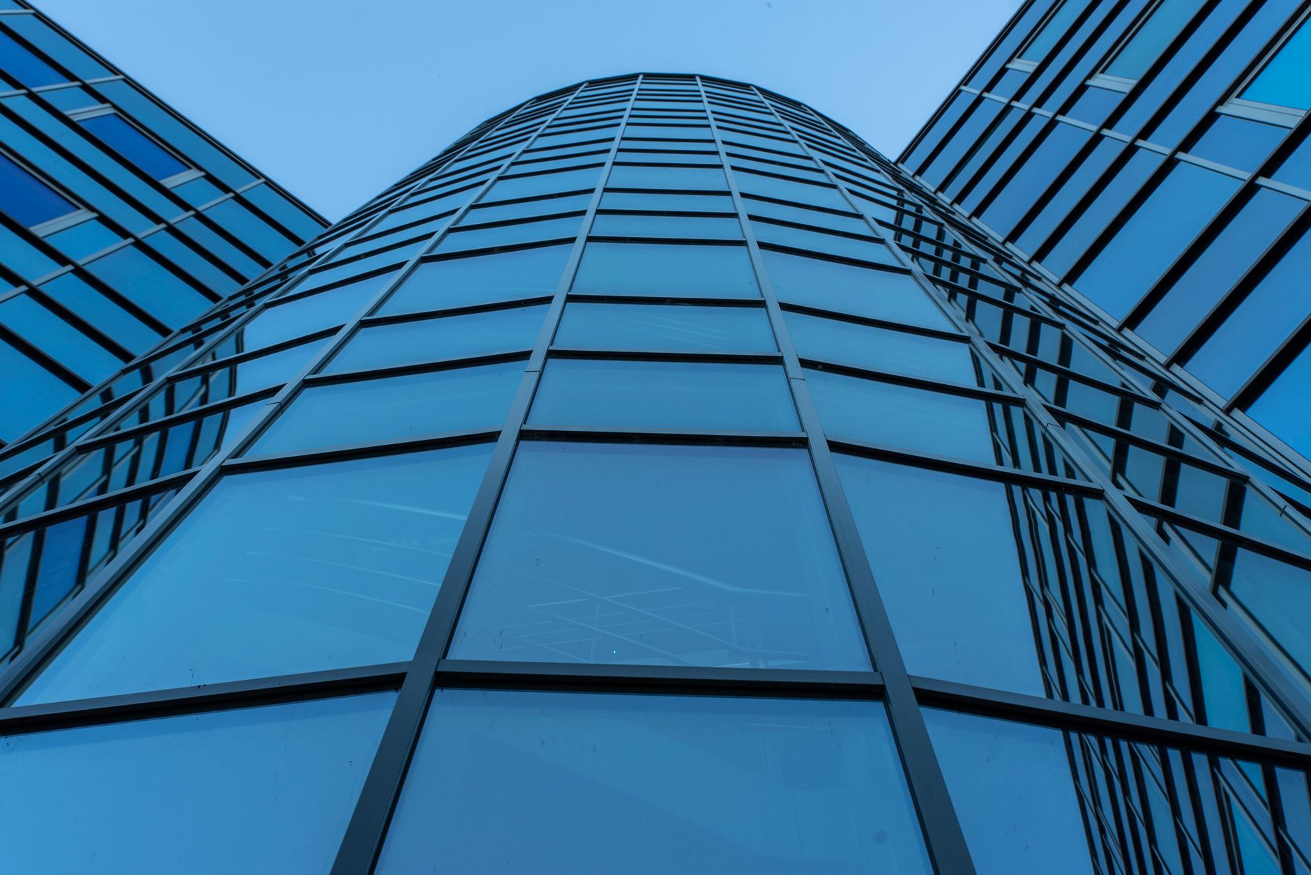 The glass facade of an office building against the sky.