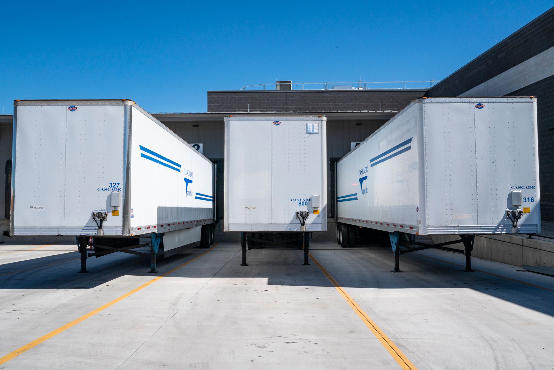 Trucks parked at a warehouse loading dock in daylight.