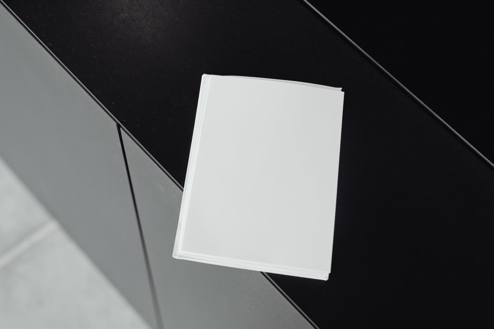 A stack of white papers on a black surface, seen from above.