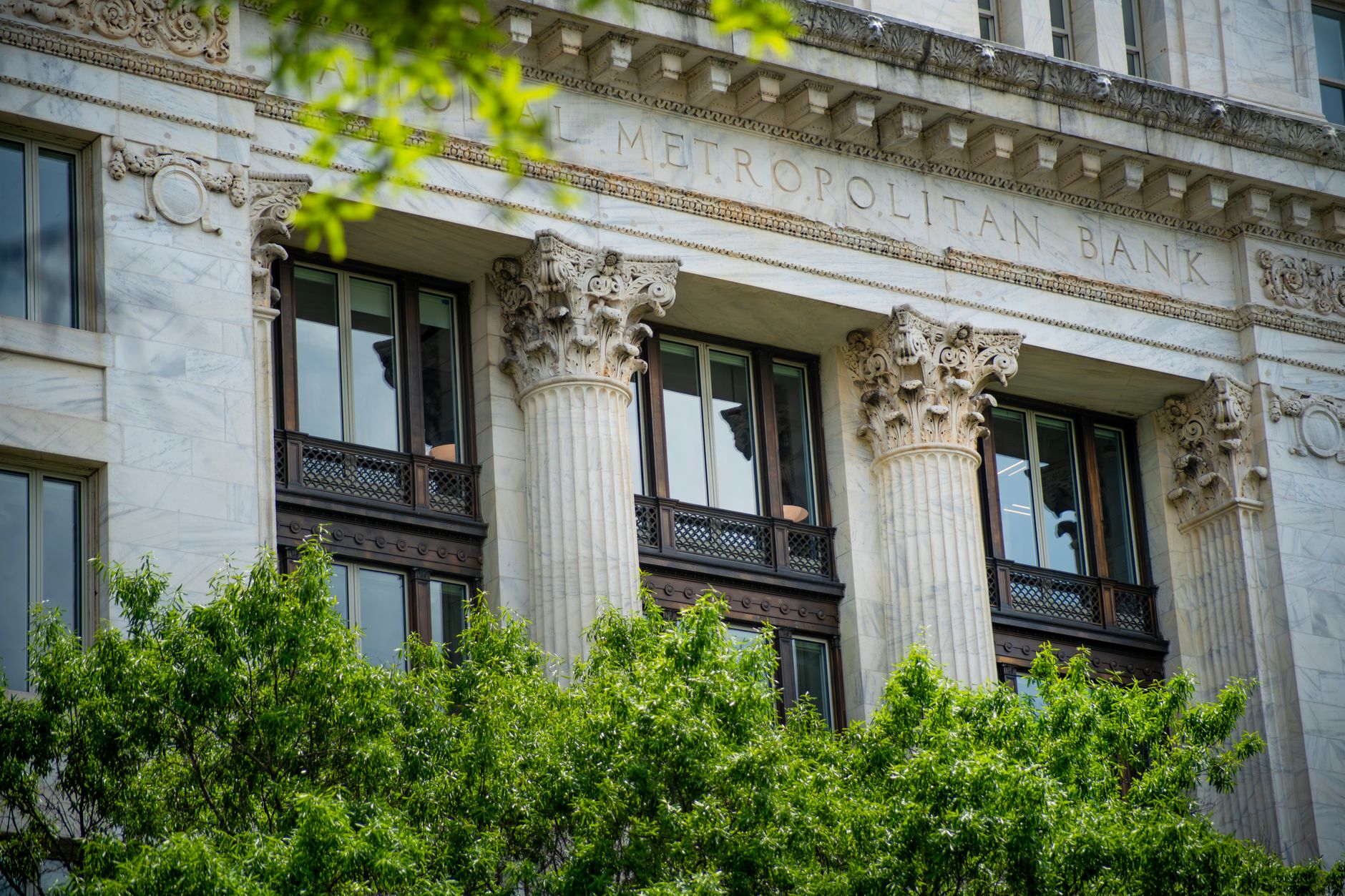 The facade of a bank branch with large windows on a city street.