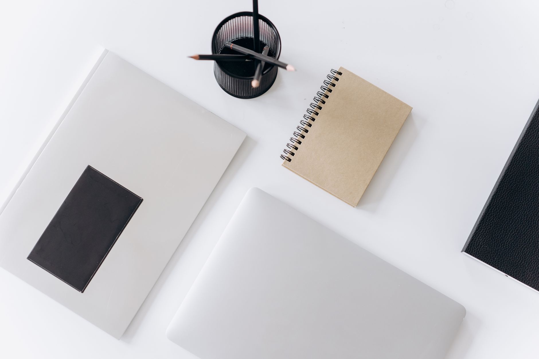 A stack of closed folders beside a laptop on an office desk.