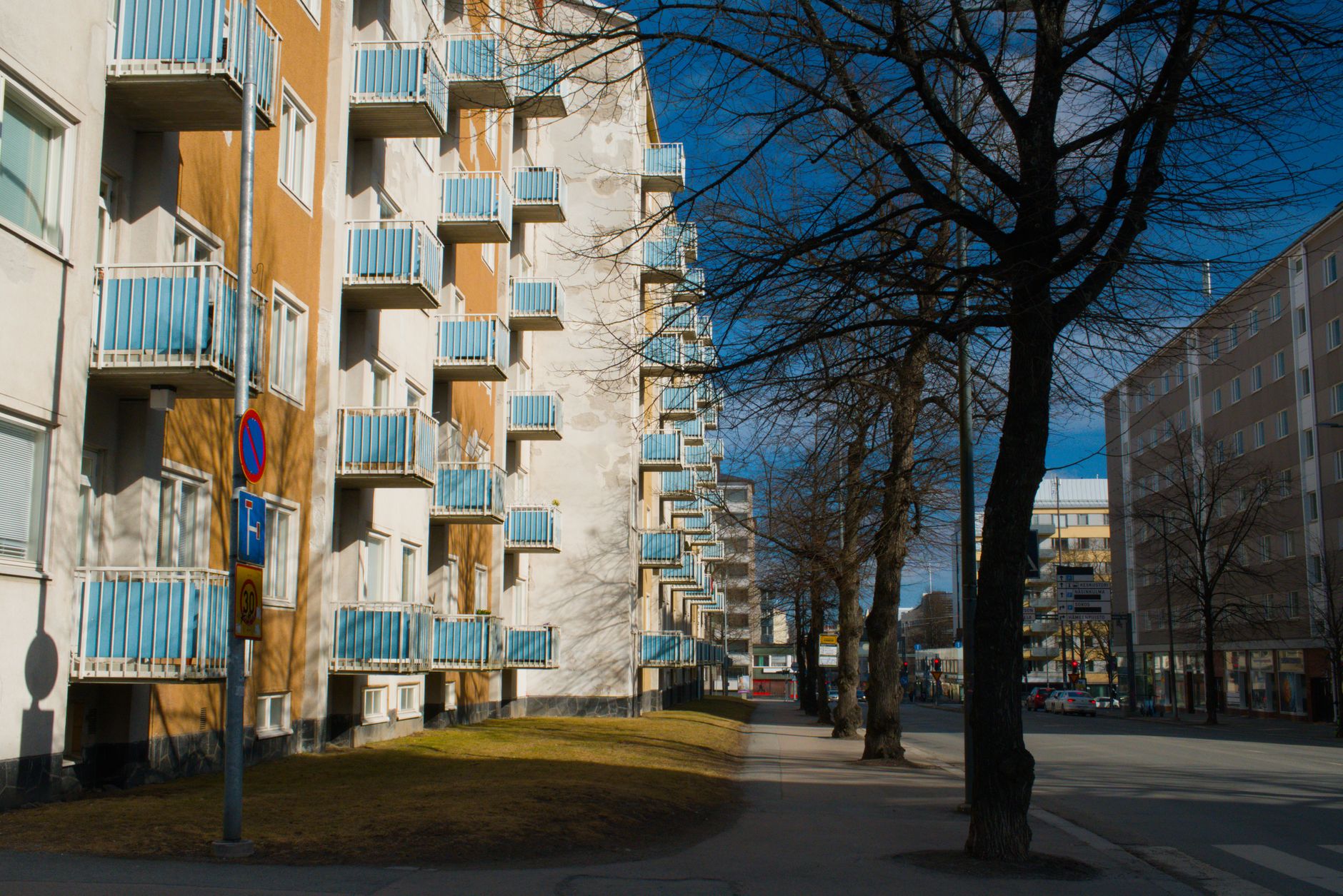 An apartment building on a tree-lined city street in daylight.