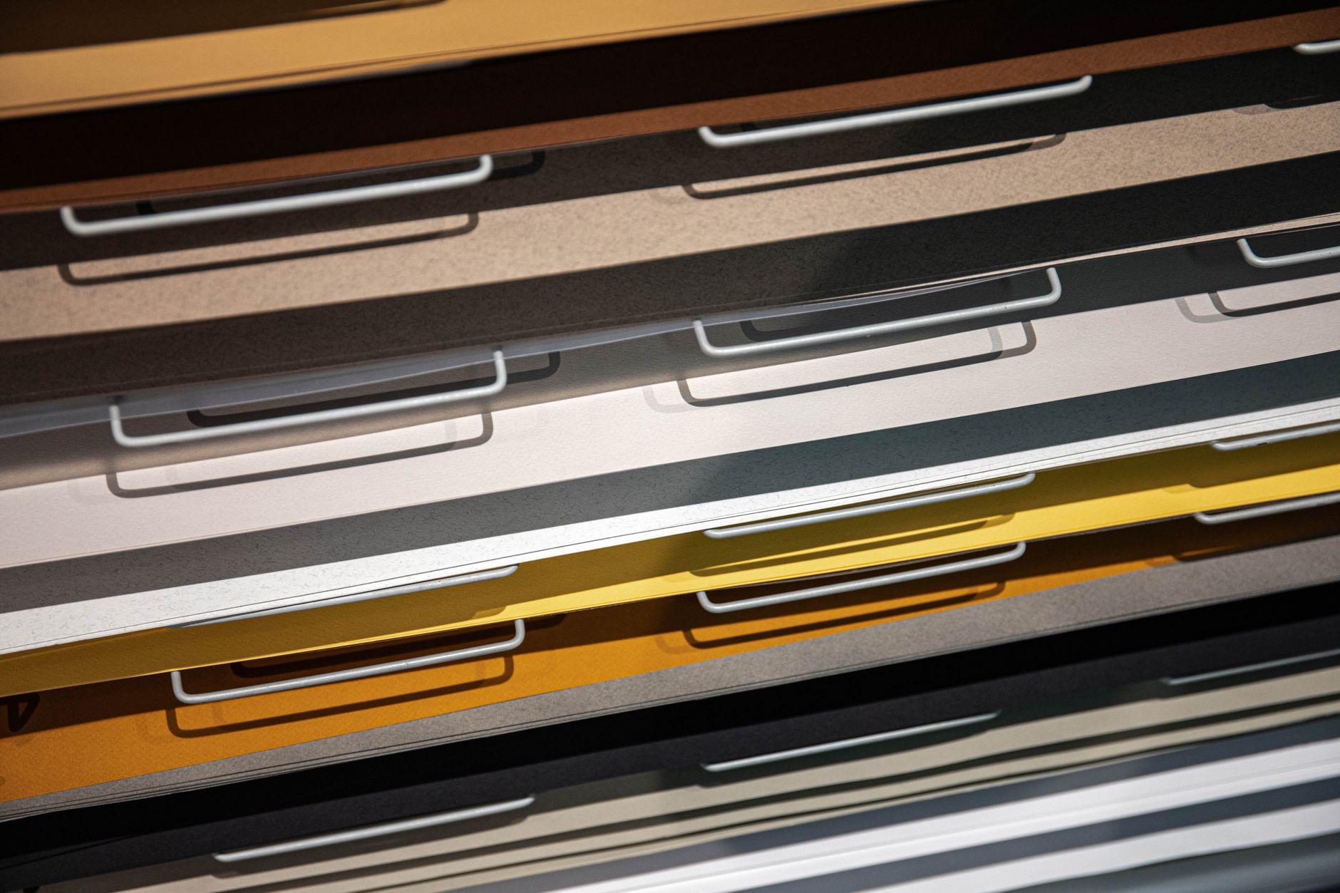 Metal drawers filled with sheets of coloured paper.