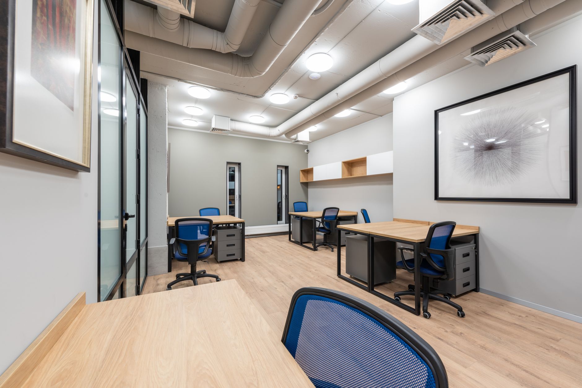 Rows of empty desks in a bright open-plan office.