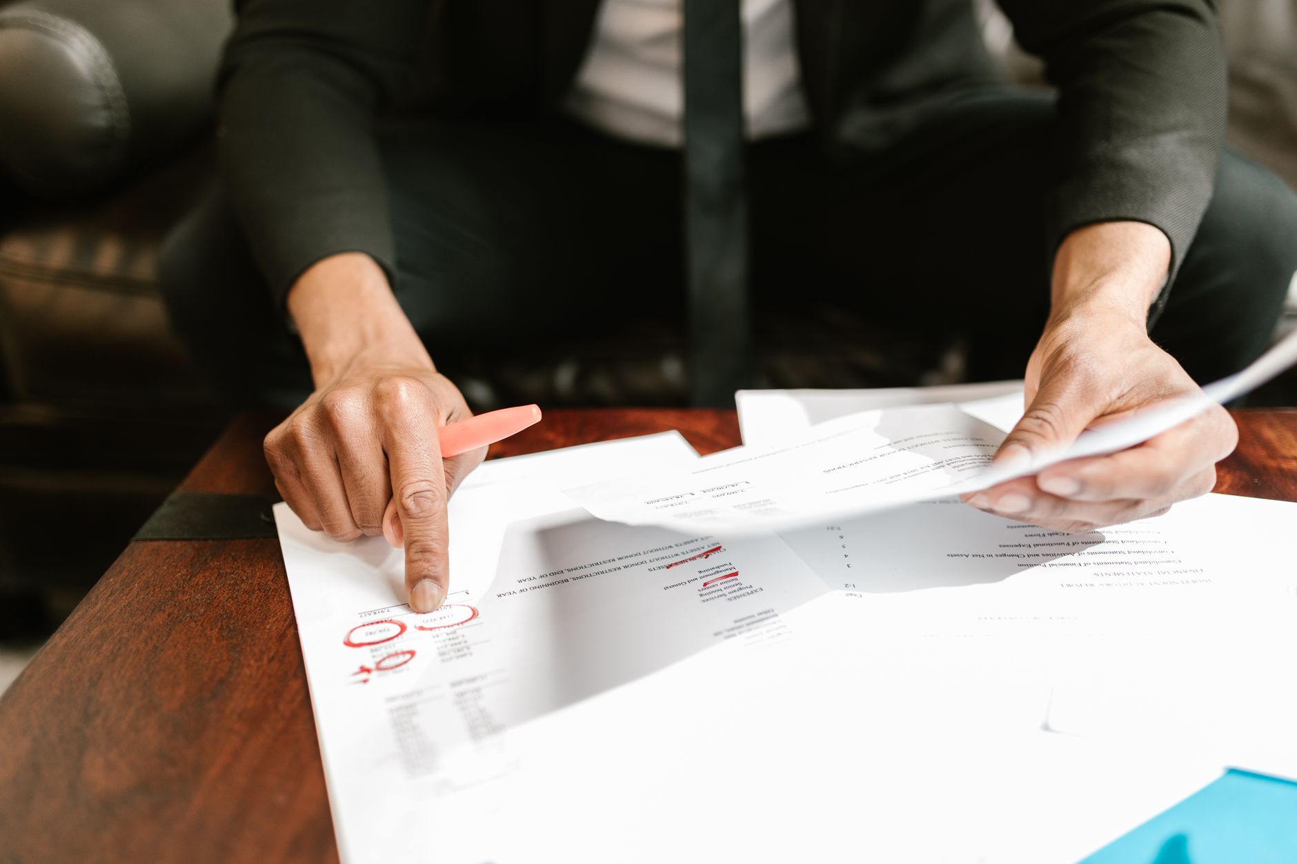 Hands reviewing printed financial documents at a desk.