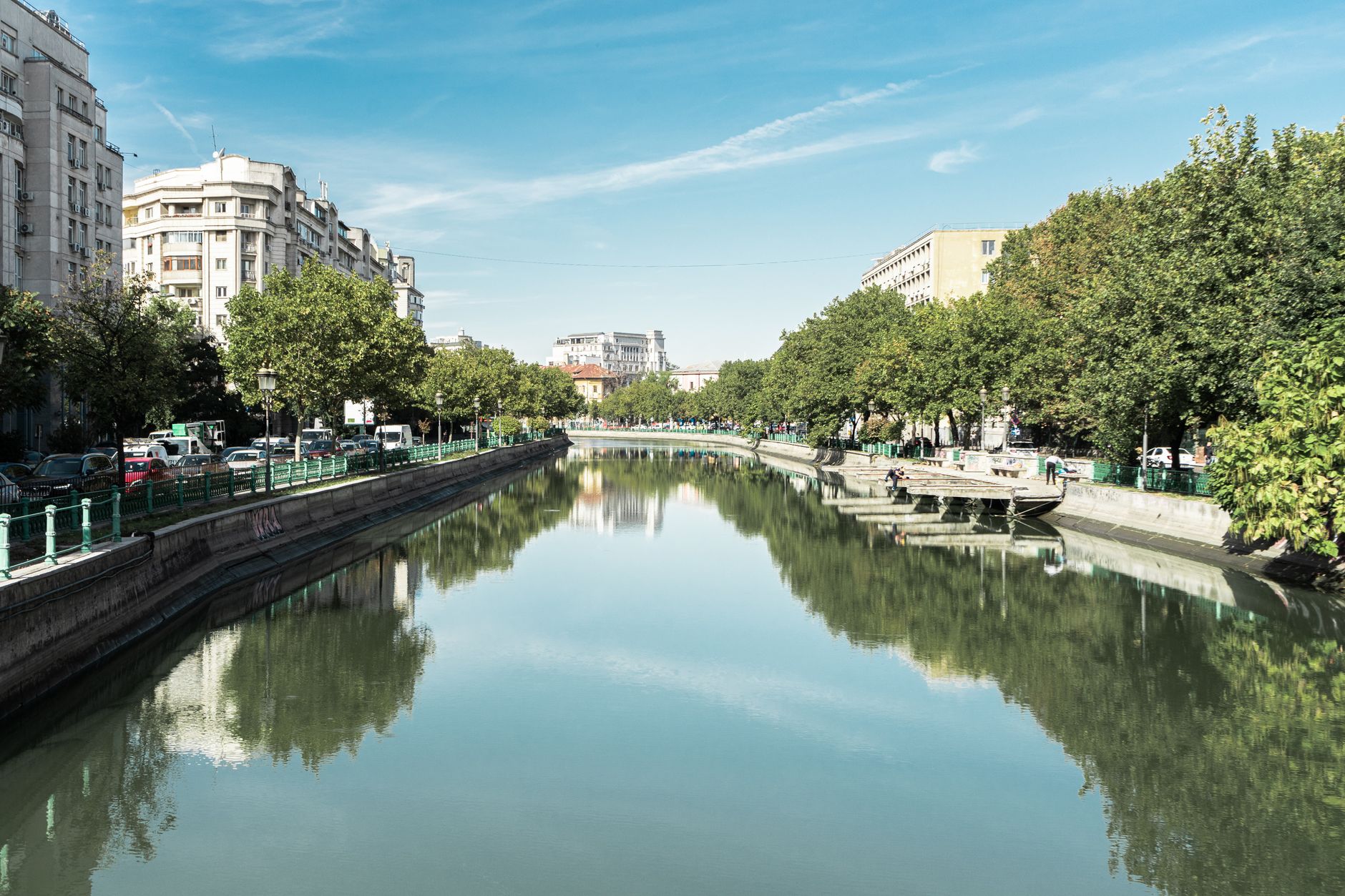 The Dâmbovița river between tree-lined embankments and city buildings in Bucharest