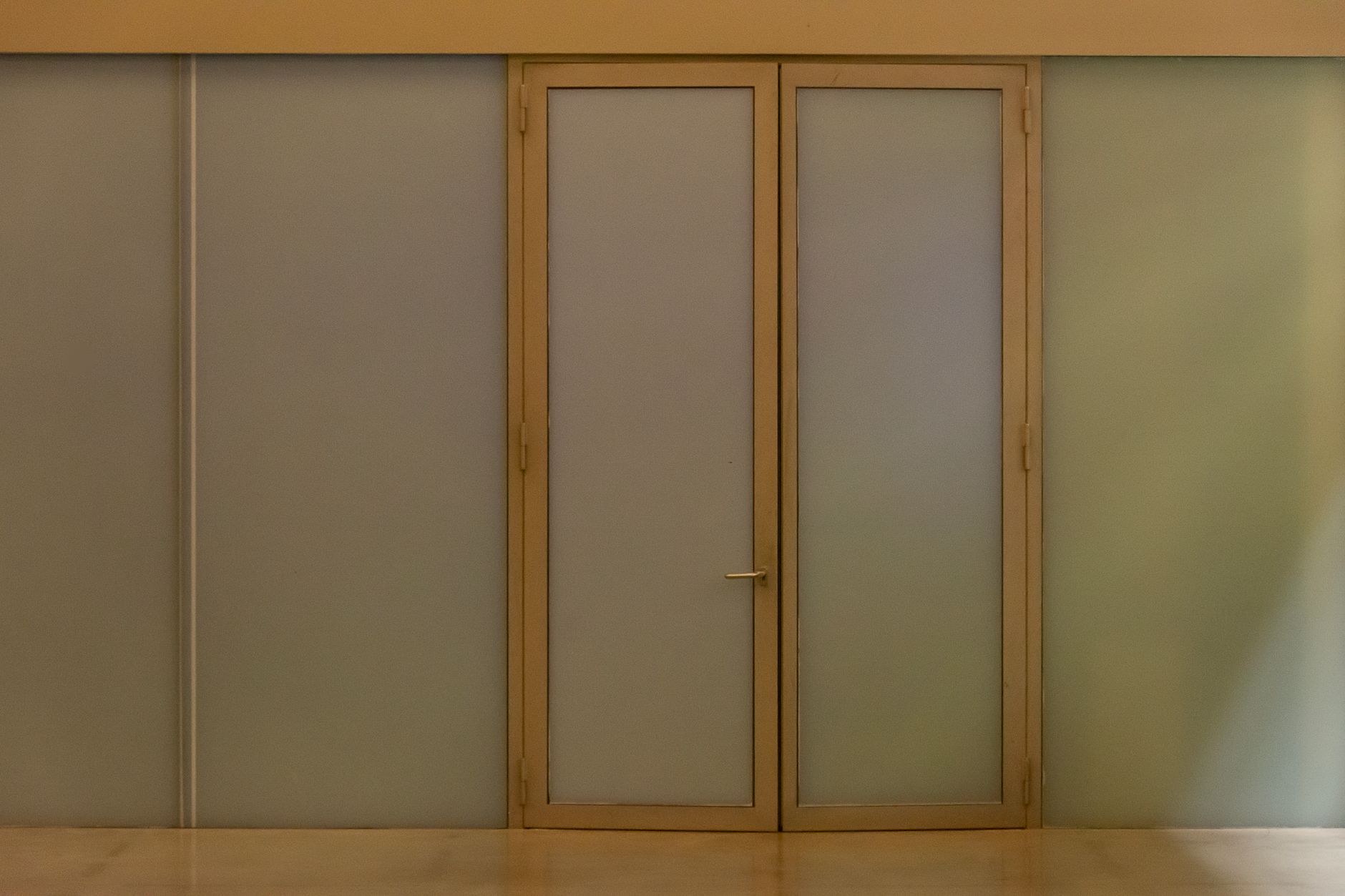 The glass entrance door of an office building in daylight.