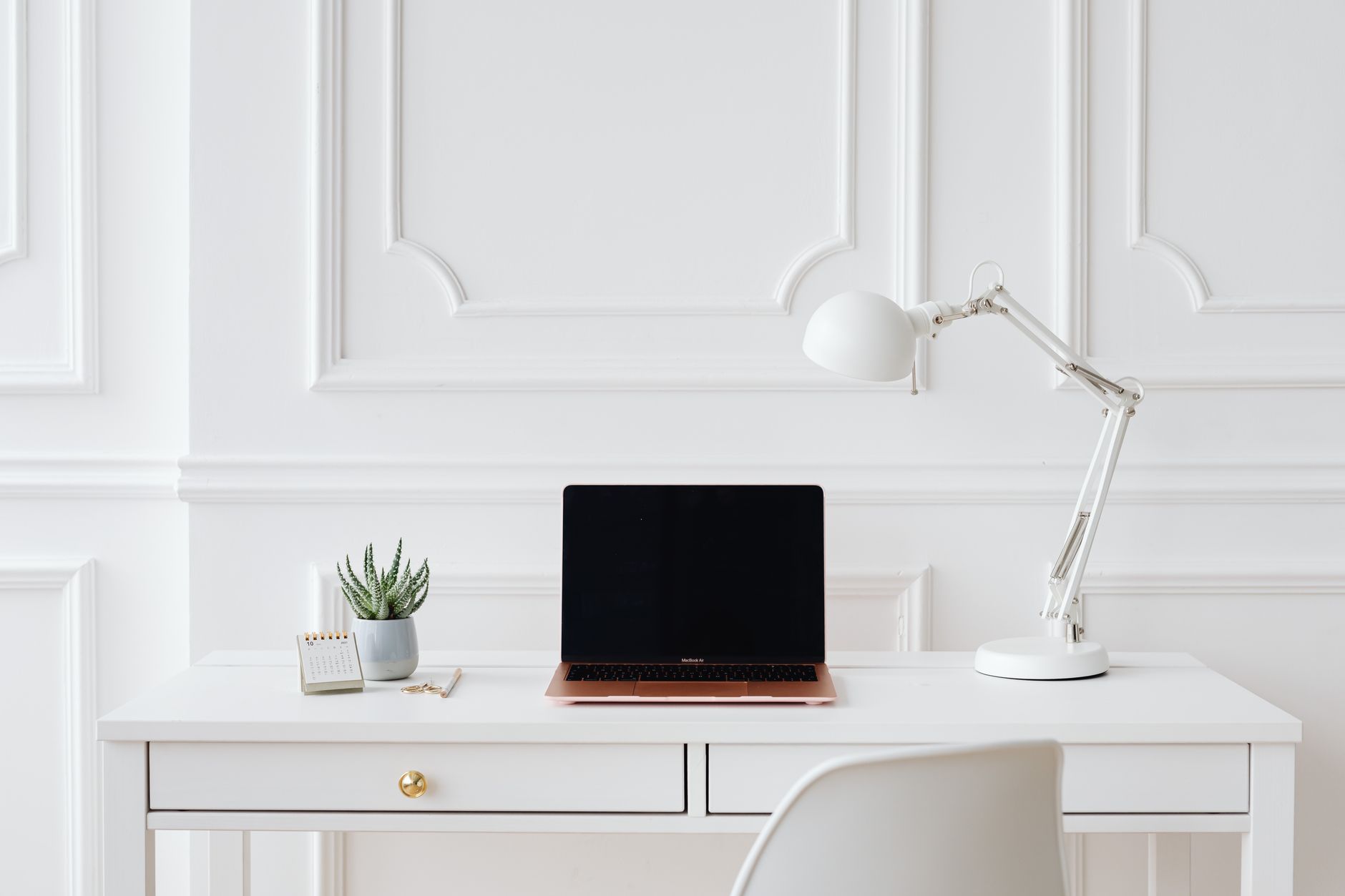 A laptop and a folder of papers on a desk.