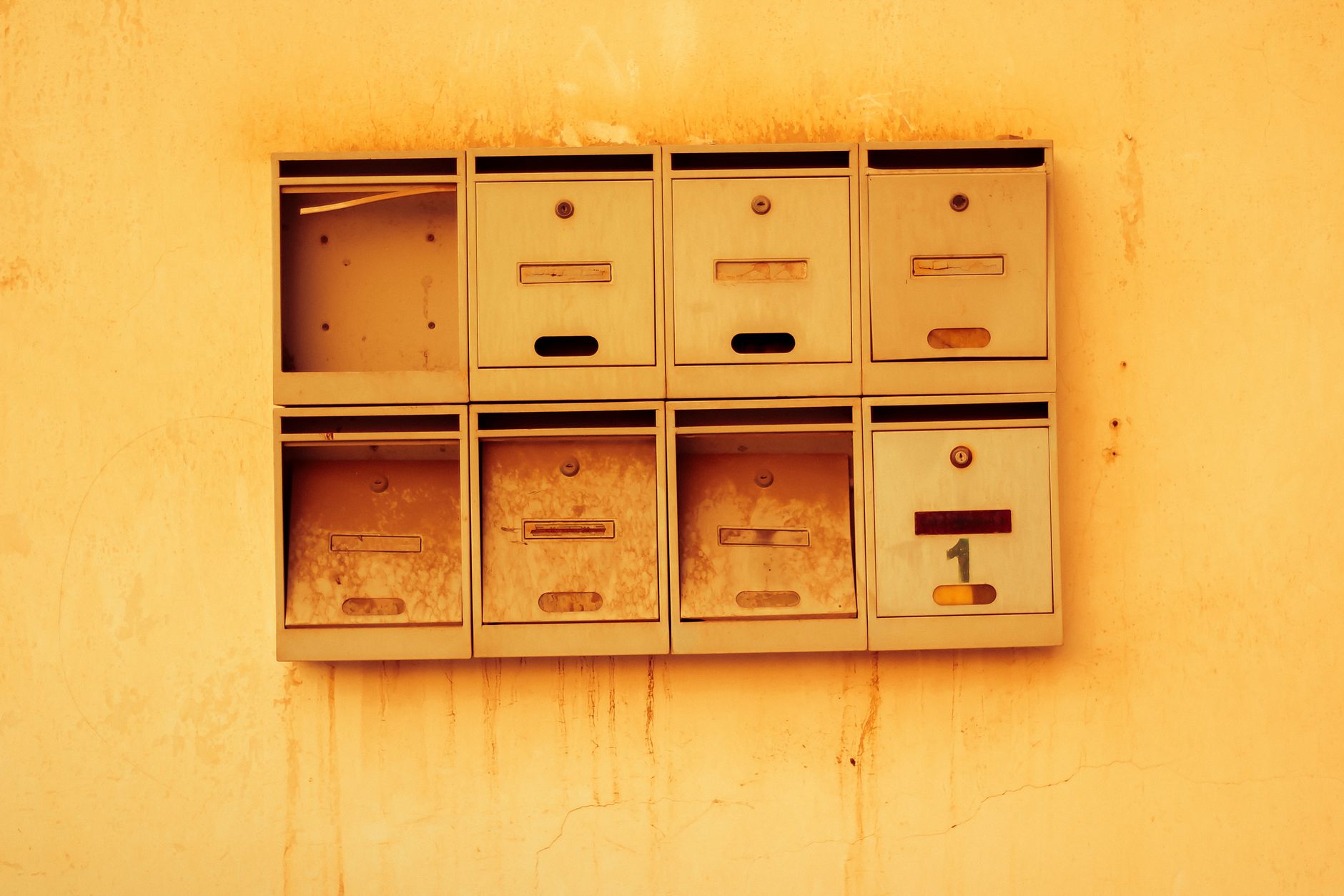Old metal mailboxes mounted on a textured wall.